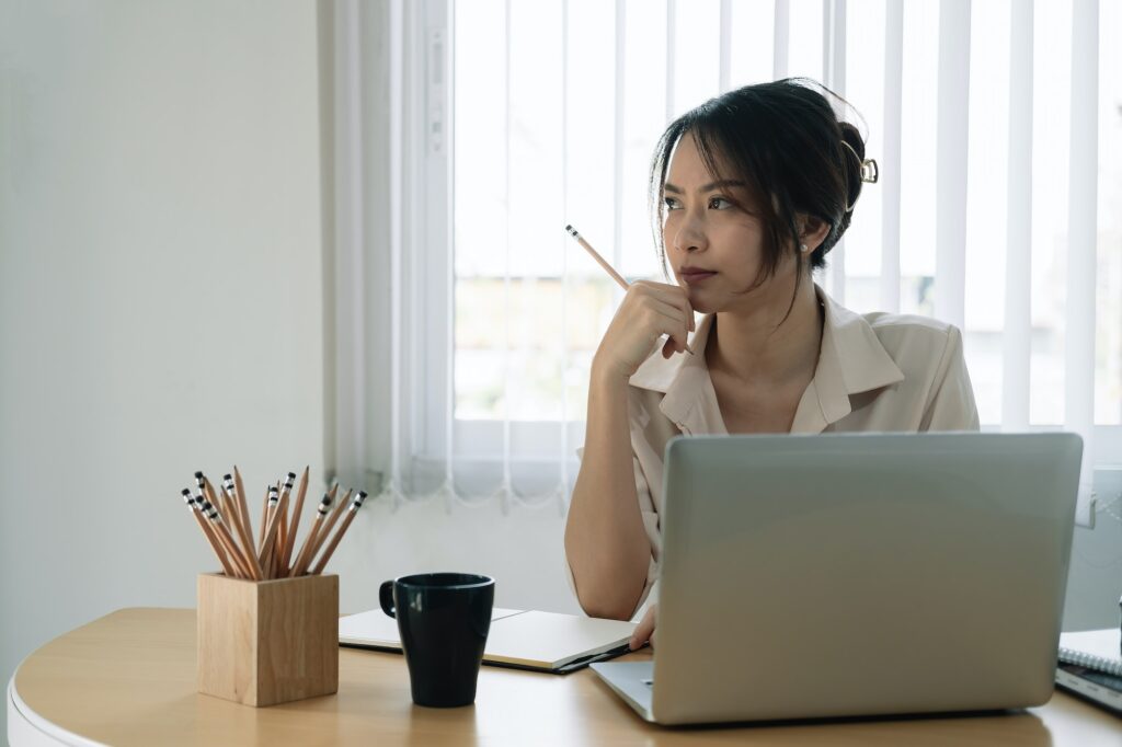 Portrait of business asian woman thinking and working with laptop computer in office