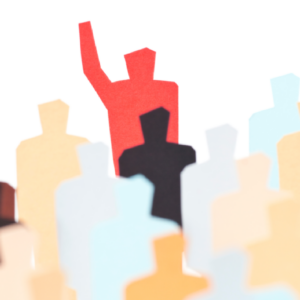 Paper cutouts of people with one in red raising their hand