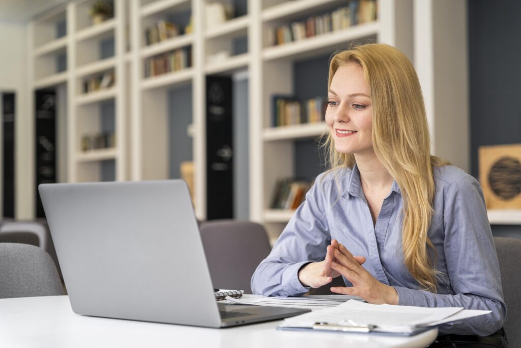 women smiling and working on laptop in front of bookshelf