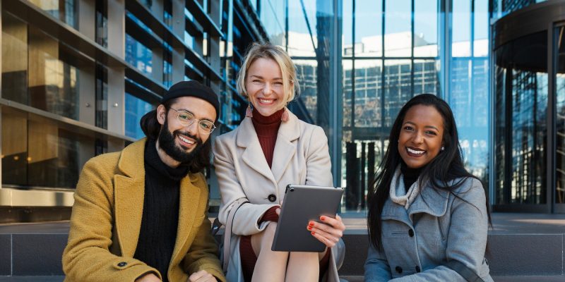 Business colleagues looking at camera and smile while sitting on the stairs outside the office Business colleagues looking at camera and smile while sitting on the stairs outside the office